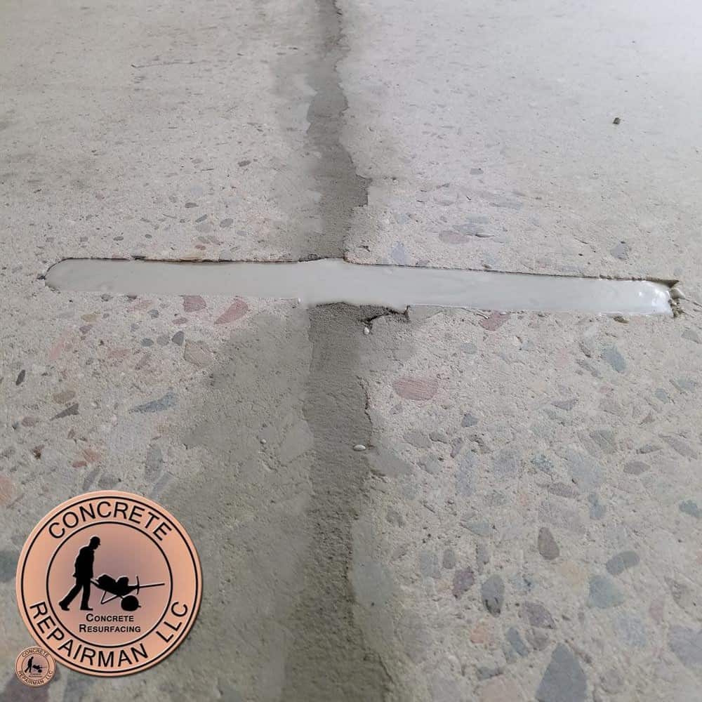 Concrete Repairman performing Concrete Crack Stitching on a structural foundation wall crack
